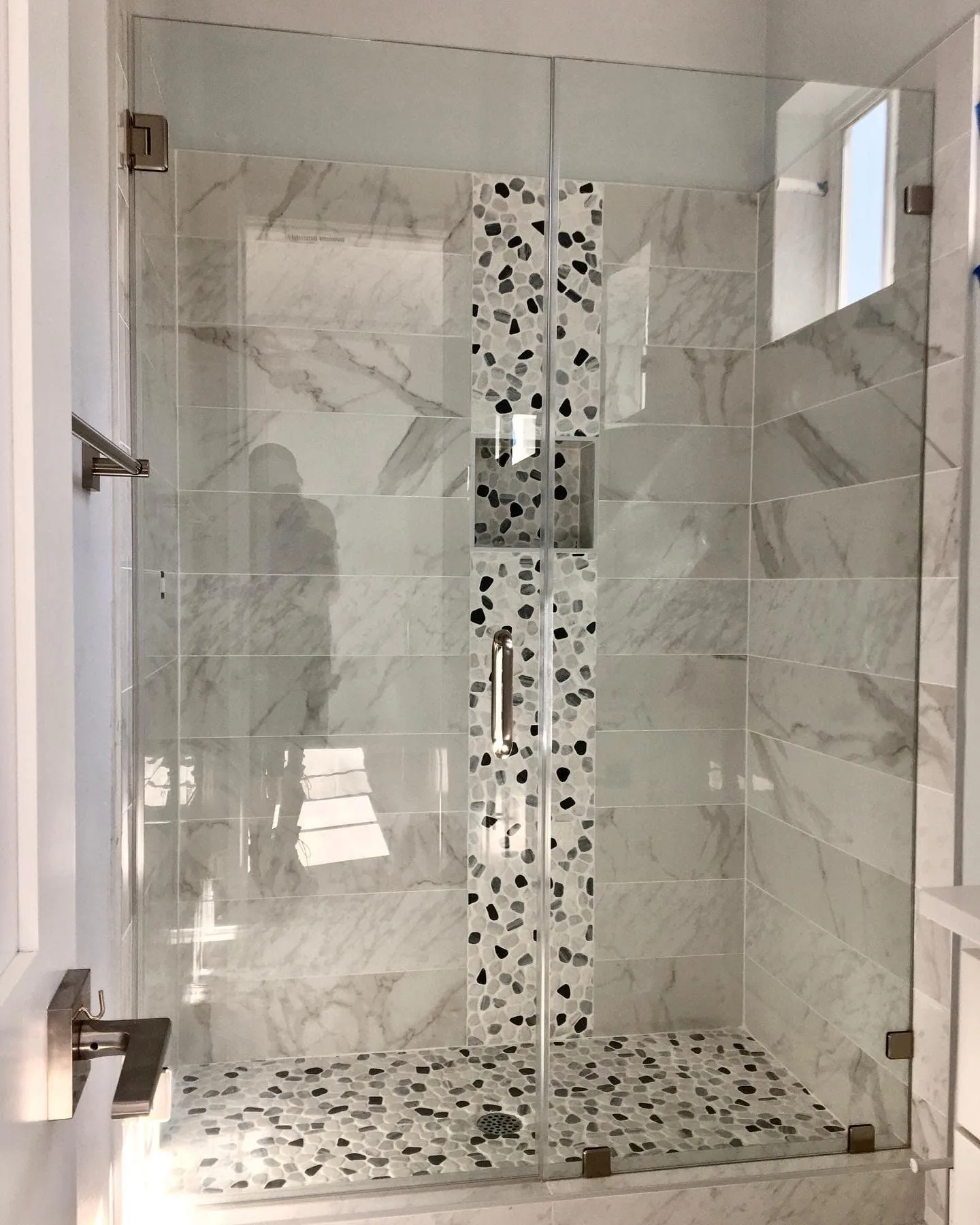 Custom shower with pebble accent strip and frameless glass enclosure