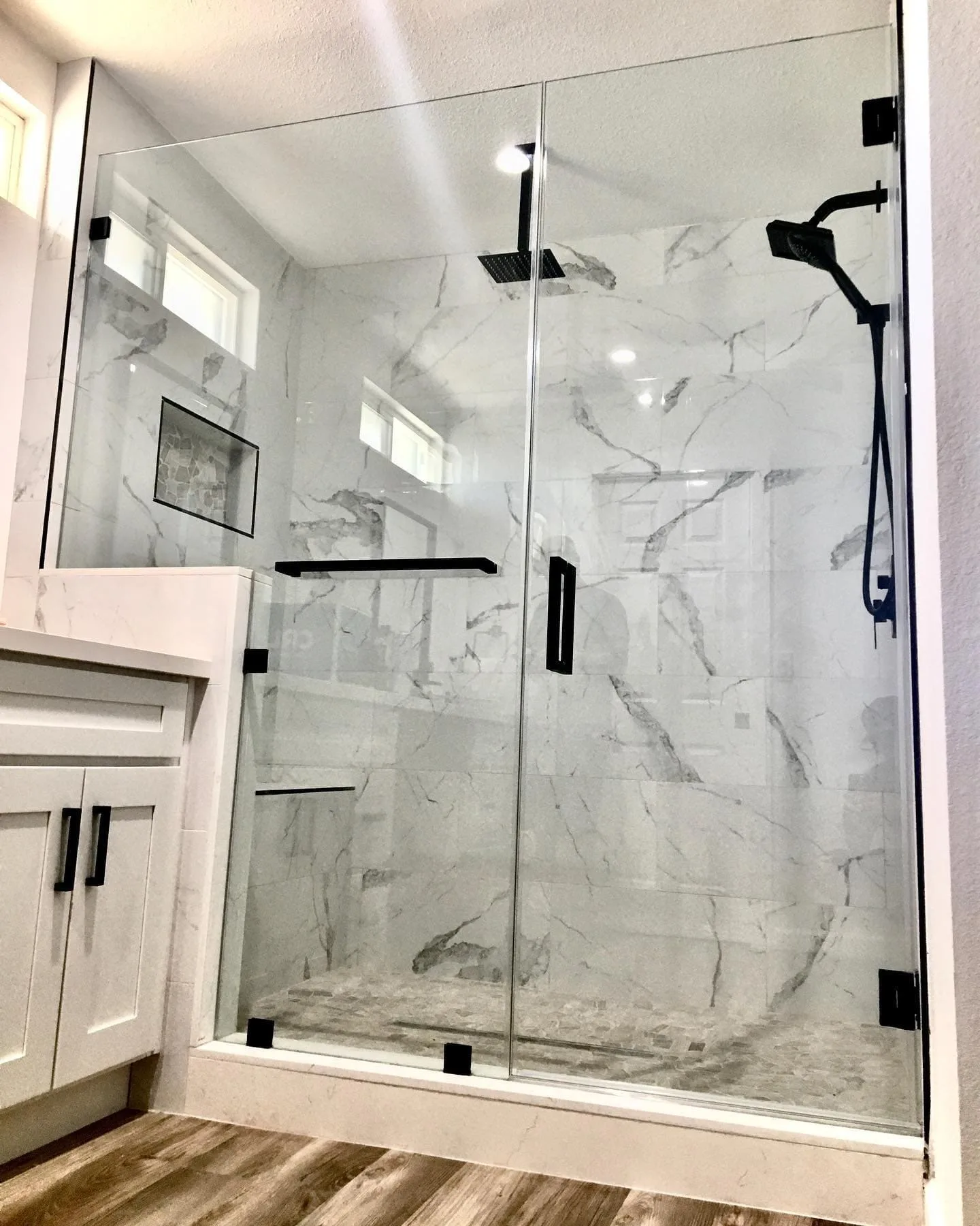 Marble shower with black hardware and built-in bench