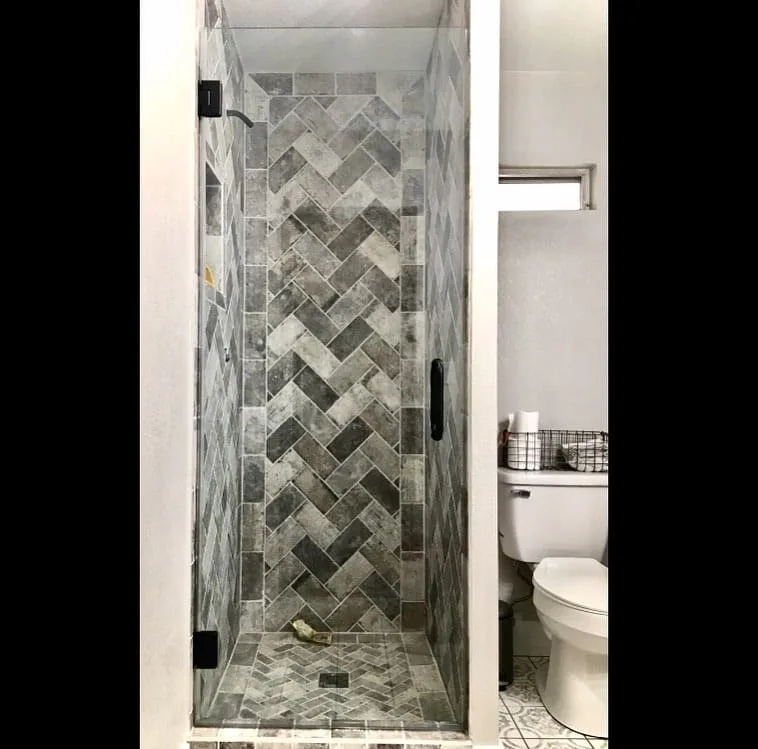 Narrow shower with herringbone accent tile and black hardware