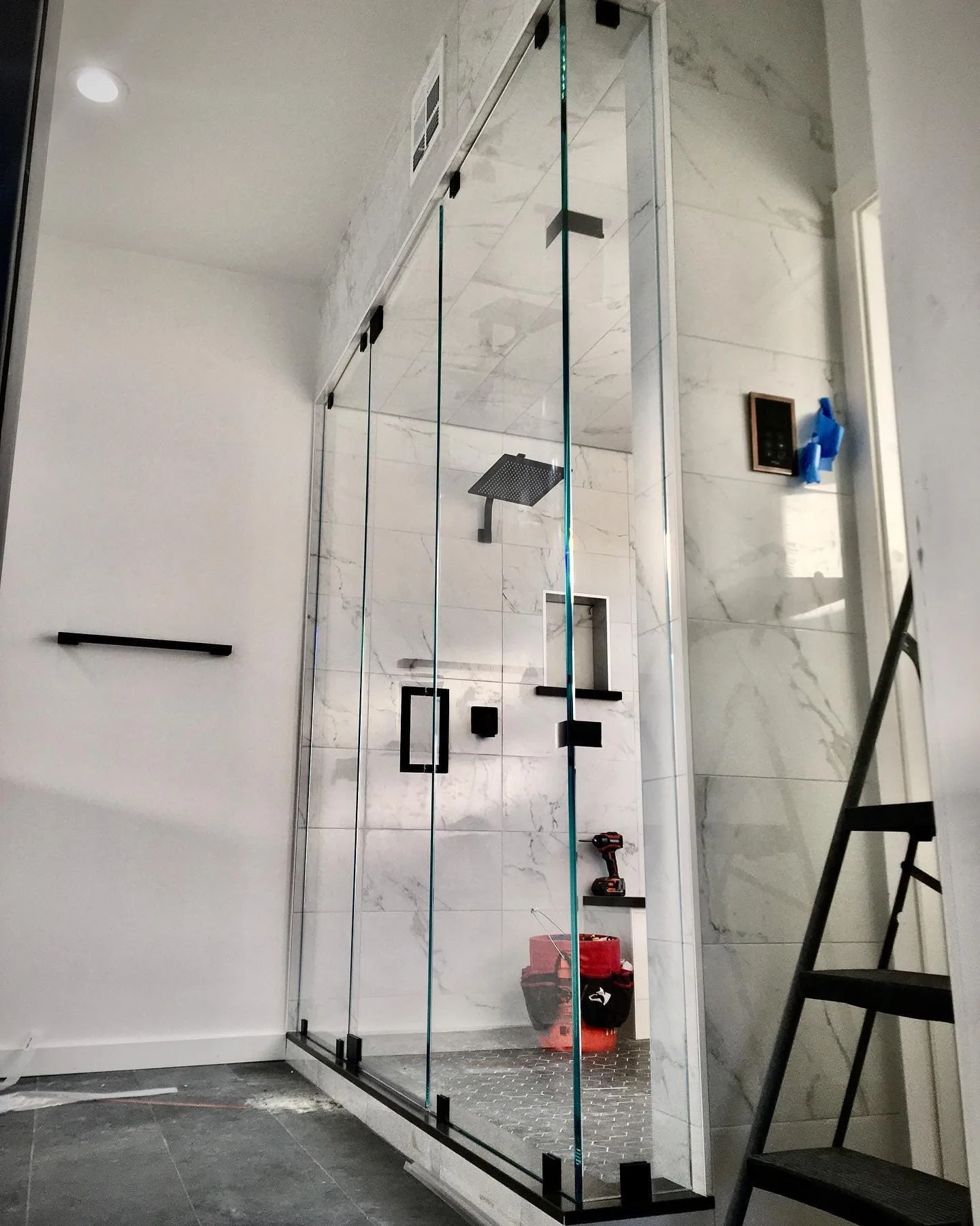 Walk-in shower installation in progress with black hardware