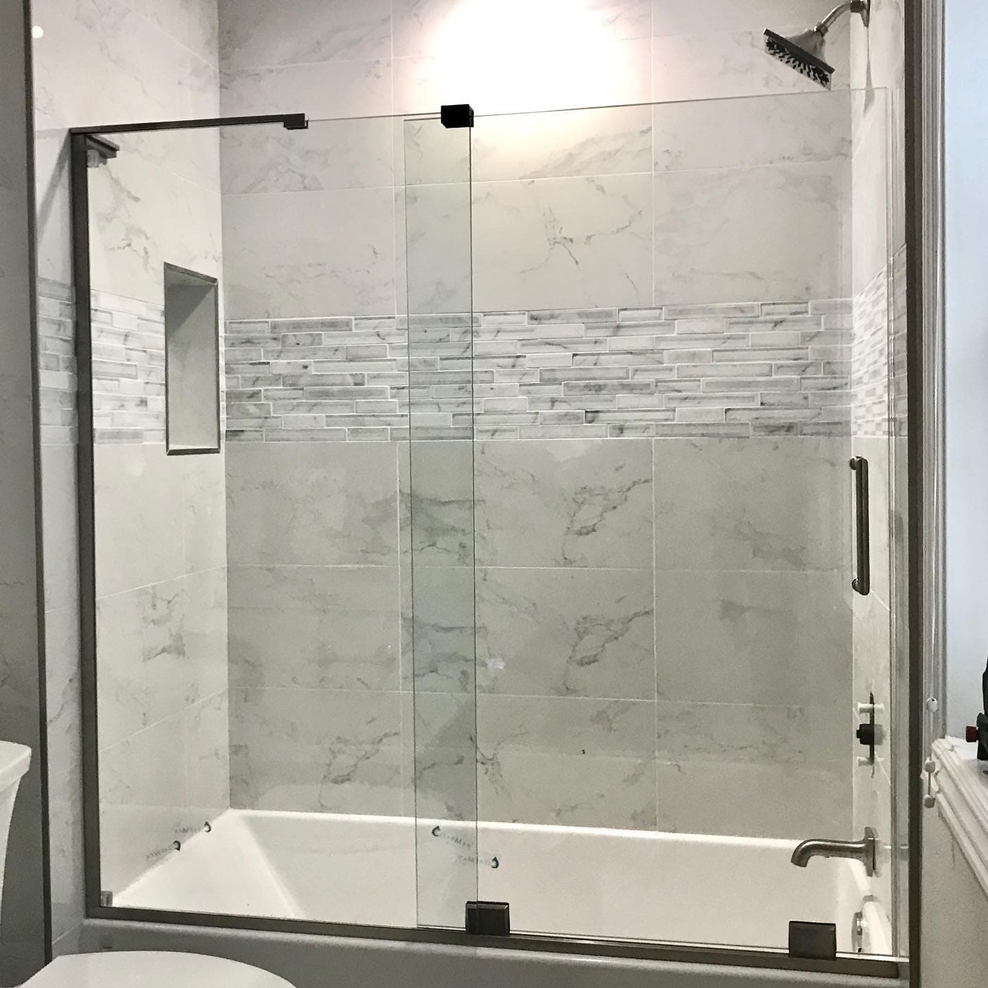 Tub enclosure with black hardware and accent tile